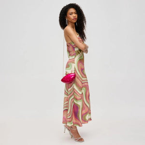 Woman wearing a colorful patterned dress holding a pink handbag on a white background