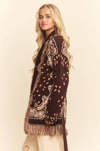 Load image into Gallery viewer, Chocolate brown tapestry-inspired jacquard knit cardigan with shawl collar, self-tie belt and multicolor fringe trim.
