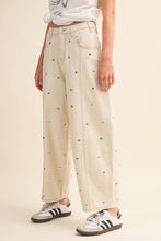 Load image into Gallery viewer, Model wearing cream barrel-leg jeans embellished with silver stud details throughout, featuring a high-rise waist and relaxed statement silhouette.
