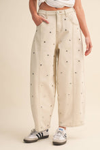 Load image into Gallery viewer, Model wearing cream barrel-leg jeans embellished with silver stud details throughout, featuring a high-rise waist and relaxed statement silhouette.
