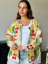 Load image into Gallery viewer, Brighten up any day with our Fruity Knit Cardigan Sweater! This cozy piece features an oversized fit for easy layering, complete with long sleeves and a ribbed hem for that perfect slouchy look. Crafted from a soft, medium-weight jacquard knit, it’s adorned with a playful multi-colored fruit pattern that’s sure to lift your spirits. With a button-up front and hip-length cut, this cardigan is designed for effortless style and comfort—One size truly fits most!
