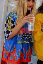 Load image into Gallery viewer, Woman wearing the All American Racing Team oversized mesh jersey featuring blue racing graphics, checkered sleeves, flame details, varsity lettering, and a large number 76 on the back.
