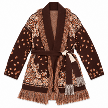 Load image into Gallery viewer, A brown knit wrap cardigan sweater with intricate paisley and floral patterns in beige and rust orange, featuring fringed trim and a matching waist tie on a white background.

