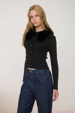 Load image into Gallery viewer, Woman wearing a black cardigan with fur collar and blue jeans on a plain background
