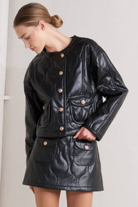 Woman wearing a Glam Expressway black leather jacket with gold buttons on a plain background