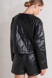 Person wearing a Glam Expressway black leather jacket and shorts on a plain background