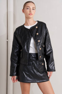 Person wearing a black leather jacket and skirt set from Glam Expressway against a plain background