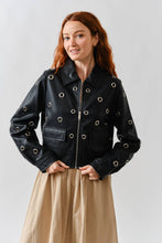 Load image into Gallery viewer, Woman wearing a Glam Expressway black &amp; silver leather jacket with grommets on a plain background

