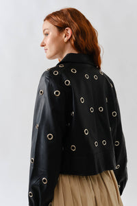 Woman wearing a Glam Expressway  black leather jacket with eyelets on a plain background