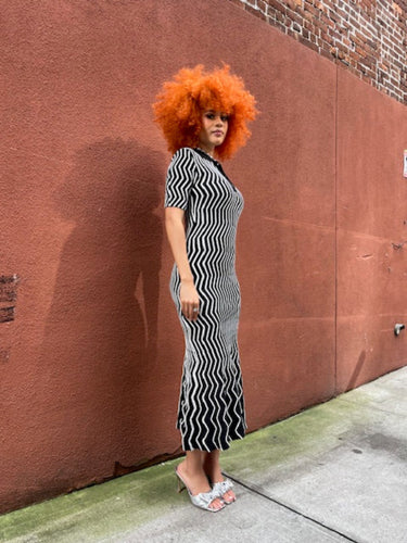 Person with red hair standing on a sidewalk