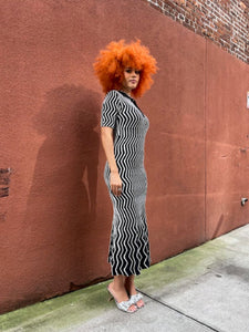 Person with red hair standing on a sidewalk