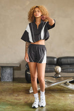 Load image into Gallery viewer, Black oversized half-zip nylon top with white mesh contrast panels, mock neckline, white piping, short sleeves, and adjustable drawcord hem.
