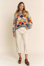 Load image into Gallery viewer, Woman wearing a colorful patterned sweater and white pants on a plain background
