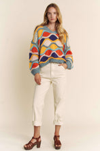 Load image into Gallery viewer, Woman wearing a colorful patterned sweater and white pants against a plain background
