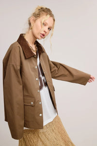 Utility-style lined jacket with a contrasting corduroy point collar, front snap closure, and front snap-flap patch pockets, designed with a boxy and oversized silhouette.