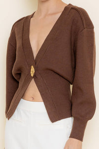 Brown knitted cardigan worn by a person on a plain background