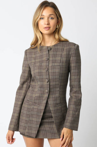 Woman wearing a brown checkered blazer and skirt set on a white background