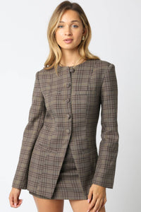 Woman wearing a brown checkered blazer and skirt set on a white background