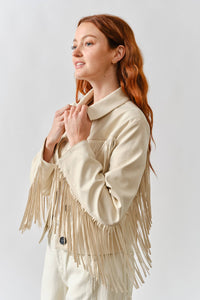Woman wearing a beige fringed sweater against a white background