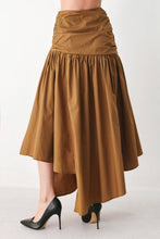 Load image into Gallery viewer, Caramel brown cotton midi skirt with a shirred waist, gathered full silhouette and dramatic asymmetrical draped hem.
