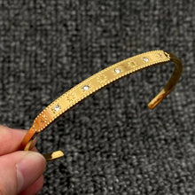 Load image into Gallery viewer, 18K gold-plated stainless steel cuff bracelet with engraved celestial starbursts and sparkling cubic zirconia accents.
