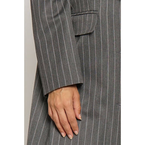 Gray pinstripe suit with a hand resting on the lapel against a white background