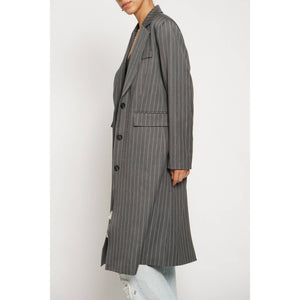 Long pinstripe coat worn by a person on a white background
