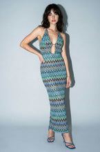 Load image into Gallery viewer, Model wearing a fitted blue and green chevron print halter maxi dress featuring a plunging front cutout, ring hardware detail, and body-skimming silhouette.
