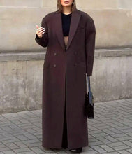 Load image into Gallery viewer, Person wearing a long dark coat standing against a stone wall.
