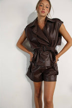 Load image into Gallery viewer, Full-length view of a female model wearing a chocolate brown faux leather matching set with a sleeveless belted jacket top and relaxed-fit shorts, styled against a white studio background.

