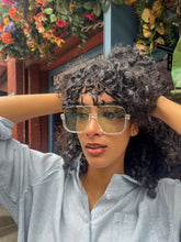 Load image into Gallery viewer, Model wearing oversized square green sunglasses with transparent frames and tinted lenses, posing in front of Glam Expressway Boutique in DUMBO, Brooklyn. Trendy summer eyewear offering UV protection and bold retro style.
