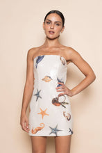 Load image into Gallery viewer, Model wearing a strapless white sequin mini dress featuring ocean-inspired seashell, starfish, and seahorse embellishments in a fitted bodycon silhouette.
