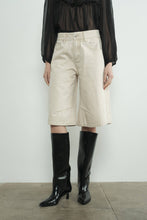 Load image into Gallery viewer, Person wearing beige denim bermuda shorts and black knee-high boots on a plain background

