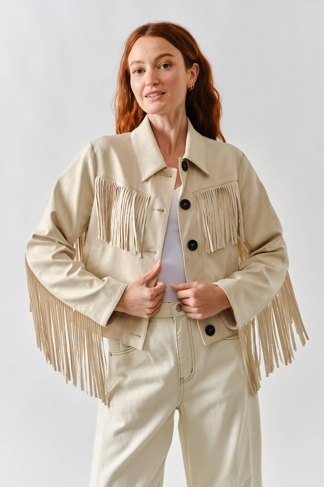 Woman wearing a beige fringed jacket on a white background