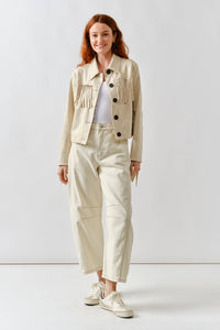 Woman wearing a beige jacket and pants standing against a white background