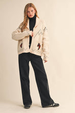 Load image into Gallery viewer, Woman wearing a cream jacket with embroidered designs on a beige background

