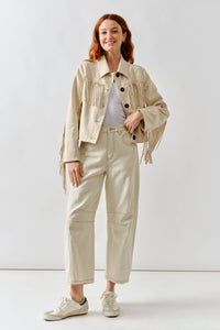 Woman wearing a beige fringed jacket and pants on a white background