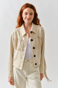 Woman wearing a beige fringed jacket against a white background