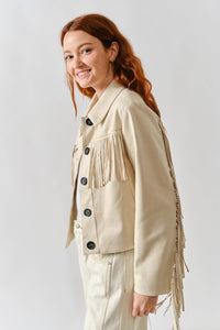 Woman wearing a beige fringed jacket on a white background