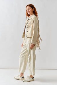 Woman wearing a beige fringed jacket and pants on a white background