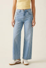 Load image into Gallery viewer, A model wearing light-wash blue wide-leg jeans, a pale yellow ribbed tank top, and white sneakers with red and brown stripes, standing against a plain beige studio background.
