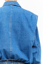 Load image into Gallery viewer, Model wearing an indigo denim bomber jacket with structured shoulders, zip-front closure, elastic hem, and gathered cuffs against a white background.
