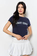 Load image into Gallery viewer, Woman wearing a navy blue t-shirt with &#39;East Coast&#39; text and a white skirt on a light gray background
