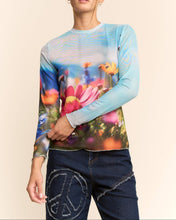 Load image into Gallery viewer, Sheer long sleeve mesh top with vibrant floral field print in soft focus colors, worn by a model.
