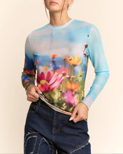 Load image into Gallery viewer, Sheer long sleeve mesh top with vibrant floral field print in soft focus colors, worn by a model.
