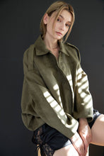 Load image into Gallery viewer, Person wearing a green jacket against a dark background
