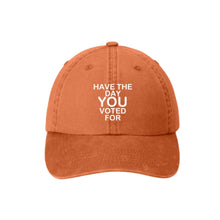 Load image into Gallery viewer, ntroducing the &quot;Have The Day You Voted For&quot; Hat in a striking rusty orange hue. This unisex cap is crafted from 100% premium cotton, ensuring comfort and durability. The front features a meticulously machine-embroidered design that makes a bold statement. 
