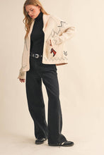 Load image into Gallery viewer, Woman wearing a patterned jacket over a black outfit on a beige background
