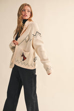 Load image into Gallery viewer, Woman wearing a cream-colored cardigan with patterned design on a beige background
