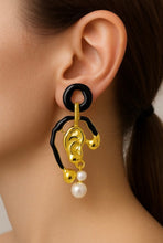 Load image into Gallery viewer, Gold and black earrings with pearl drop worn by a person
